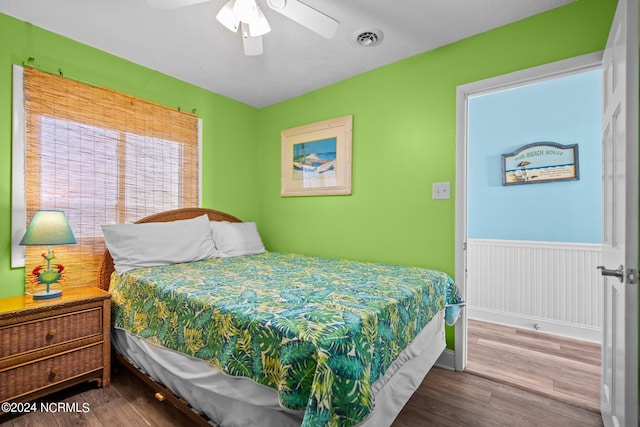 503 Pelican Ct Unit 503, Kure Beach, NC 28449 - bedroom featuring a ceiling fan, a wainscoted wall, wood finished floors, and visible vents