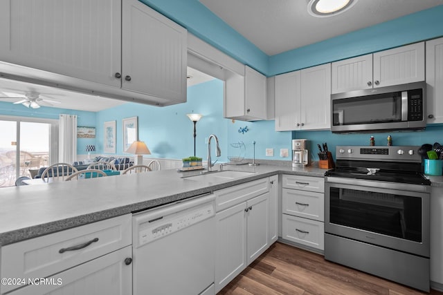 kitchen with ceiling fan, hardwood / wood-style floors, sink, appliances with stainless steel finishes, and white cabinetry