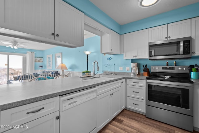 503 Pelican Ct Unit 503, Kure Beach, NC 28449 - kitchen with a ceiling fan, wood finished floors, a sink, white cabinetry, and appliances with stainless steel finishes
