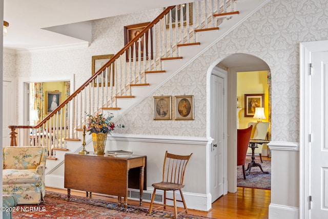 staircase with hardwood / wood-style floors and crown molding