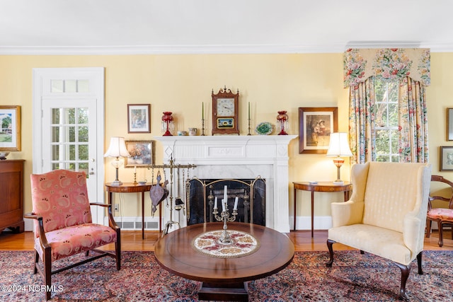 sitting room with a premium fireplace, ornamental molding, and hardwood / wood-style flooring