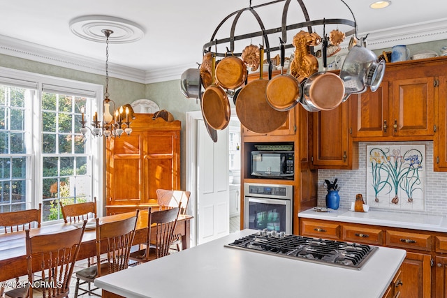 kitchen with pendant lighting, crown molding, stainless steel appliances, and a kitchen island