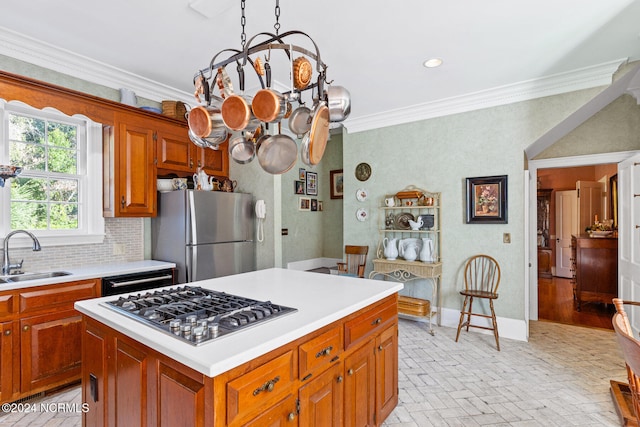 kitchen with appliances with stainless steel finishes, sink, a center island, crown molding, and decorative backsplash