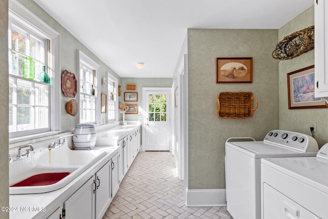 clothes washing area with sink, a healthy amount of sunlight, cabinets, and washing machine and clothes dryer