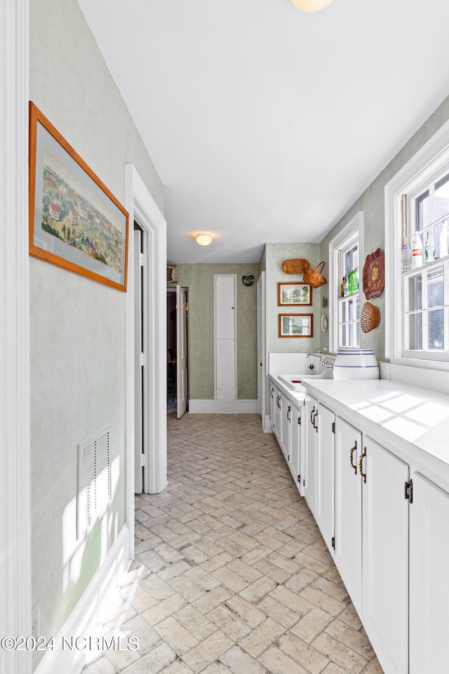 kitchen with tile counters, white cabinets, and sink