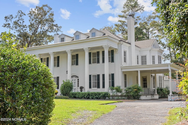 neoclassical home with covered porch and a front lawn