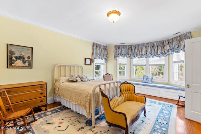 bedroom featuring crown molding, multiple windows, and light wood-type flooring