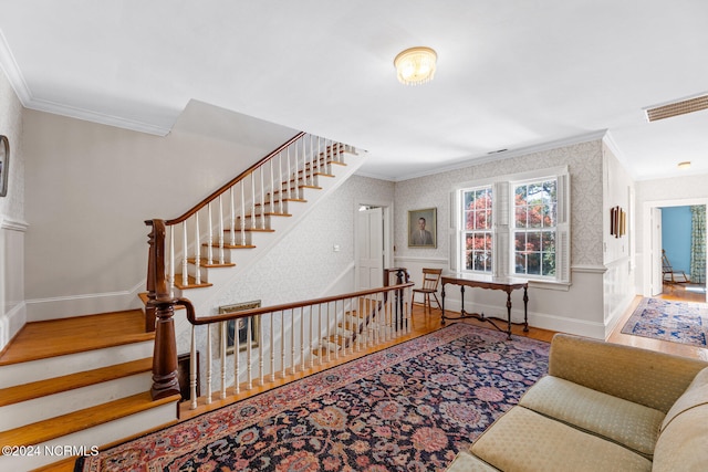 stairs with ornamental molding and hardwood / wood-style floors