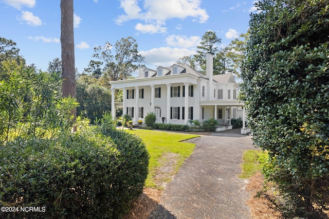 neoclassical home featuring a porch and a front lawn