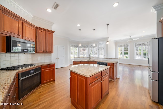 kitchen with hanging light fixtures, a center island, light stone counters, black appliances, and crown molding