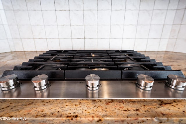 room details with decorative backsplash, stovetop, and stainless steel counters