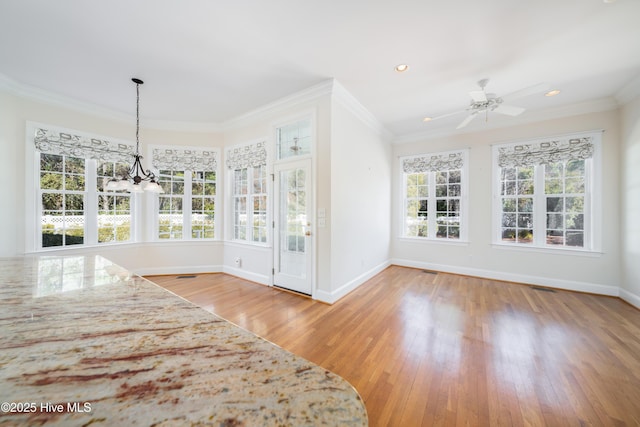 unfurnished dining area with hardwood / wood-style flooring, ceiling fan with notable chandelier, and ornamental molding