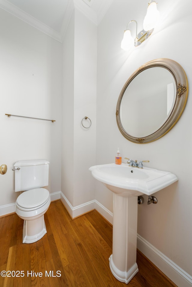 bathroom with wood-type flooring, ornamental molding, and toilet