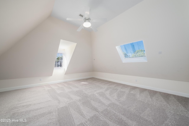 bonus room with light carpet, ceiling fan, and vaulted ceiling with skylight