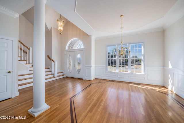 entryway featuring hardwood / wood-style floors, a wealth of natural light, a chandelier, and ornate columns