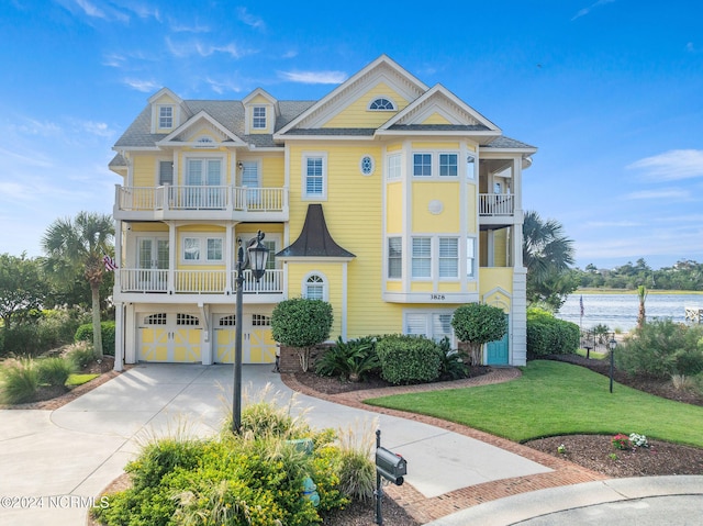 view of front of property with a water view, a balcony, a front lawn, and a garage