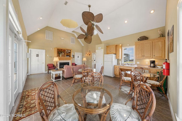 tiled dining room featuring high vaulted ceiling, sink, and ceiling fan