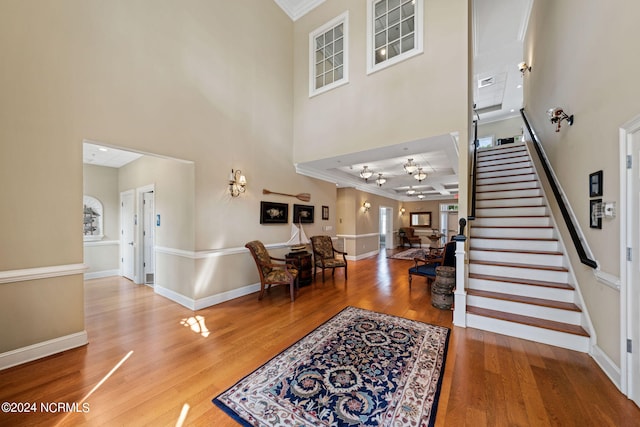 entryway with ornamental molding, hardwood / wood-style floors, and a high ceiling