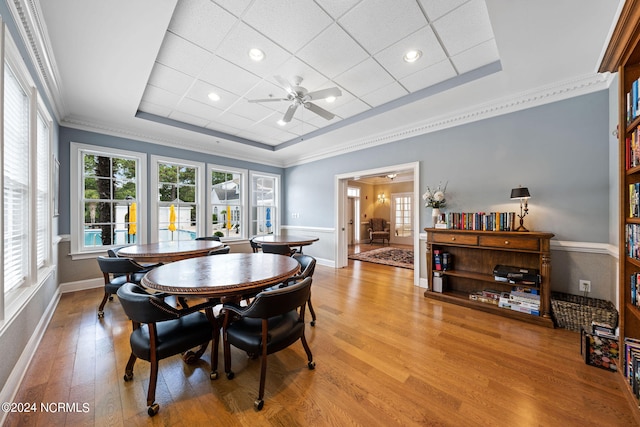 dining space featuring crown molding, a tray ceiling, light wood-type flooring, and ceiling fan