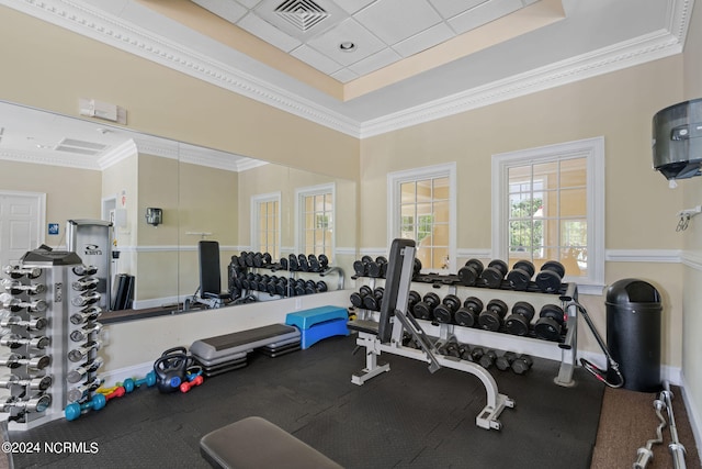 gym with ornamental molding and a tray ceiling