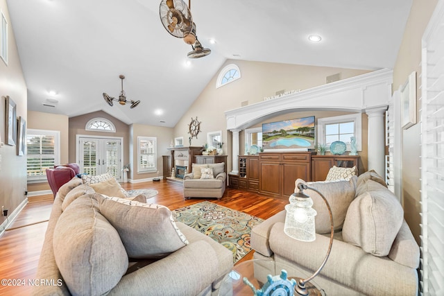 living room with french doors, hardwood / wood-style floors, ornate columns, and vaulted ceiling