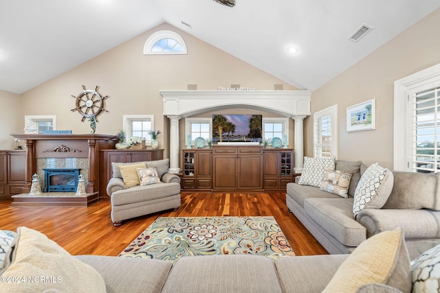 living room featuring high vaulted ceiling, hardwood / wood-style flooring, and decorative columns