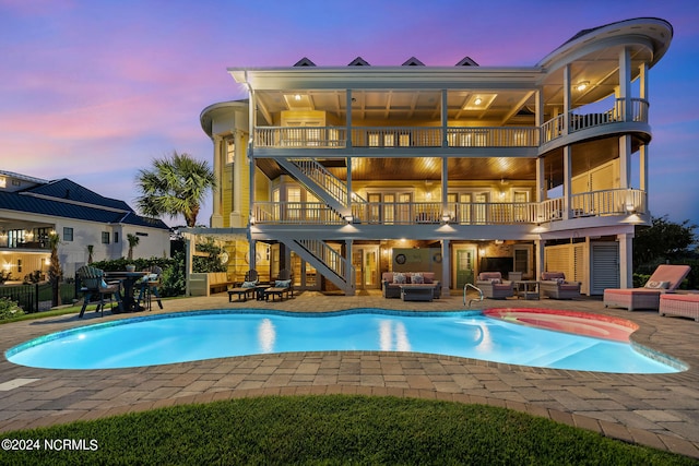 pool at dusk featuring a patio, a hot tub, and outdoor lounge area