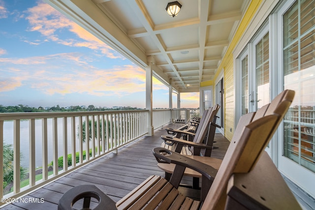 deck at dusk featuring a water view