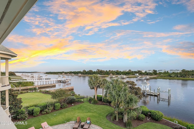 view of dock with a lawn and a water view