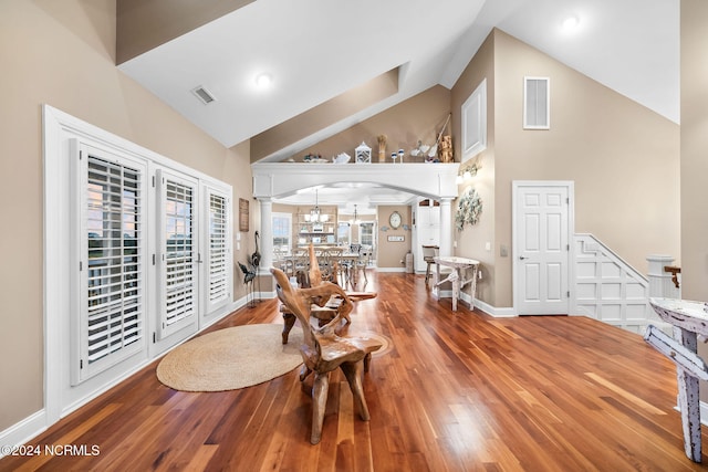 dining space featuring decorative columns, high vaulted ceiling, and wood-type flooring