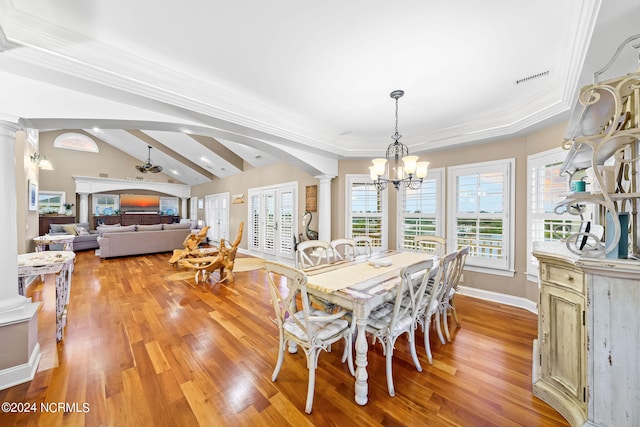 dining space featuring vaulted ceiling, light hardwood / wood-style flooring, ornamental molding, ceiling fan with notable chandelier, and ornate columns