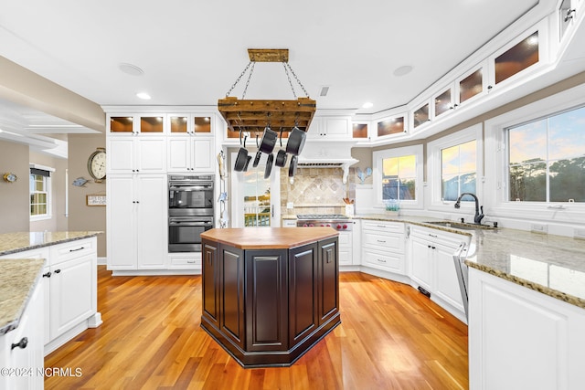 kitchen with light hardwood / wood-style flooring, stainless steel double oven, pendant lighting, and a kitchen island