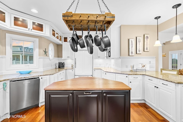 kitchen featuring a center island, decorative light fixtures, light wood-type flooring, stainless steel dishwasher, and white cabinets