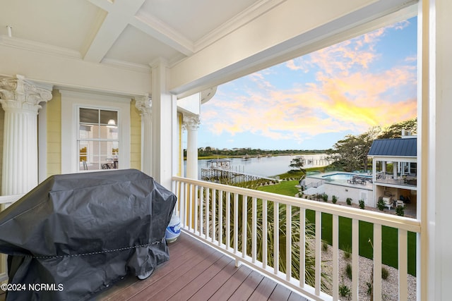 deck at dusk with area for grilling and a water view