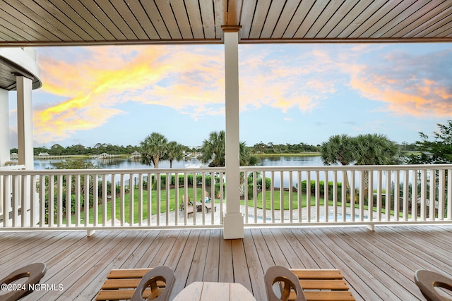 deck at dusk featuring a water view