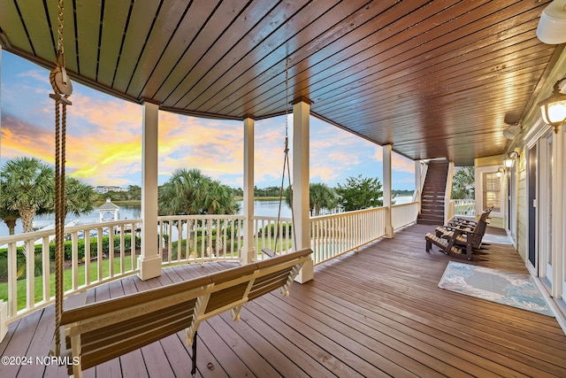 deck at dusk featuring a water view