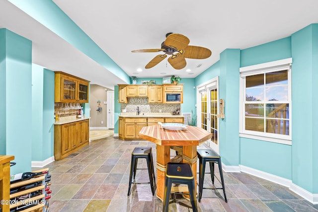 kitchen with black microwave, ceiling fan, sink, and backsplash