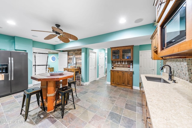 kitchen featuring sink, stainless steel fridge, decorative backsplash, and a barn door