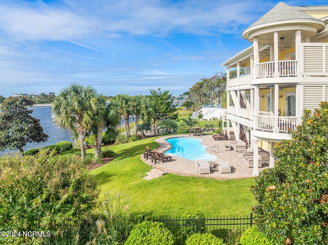 view of swimming pool with a patio, a water view, and a lawn