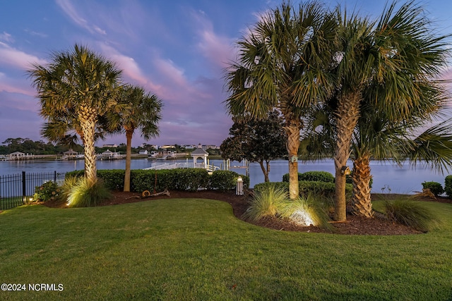 yard at dusk featuring a water view