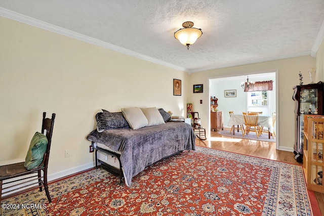 living room with ornamental molding, light wood-type flooring, an inviting chandelier, and a textured ceiling