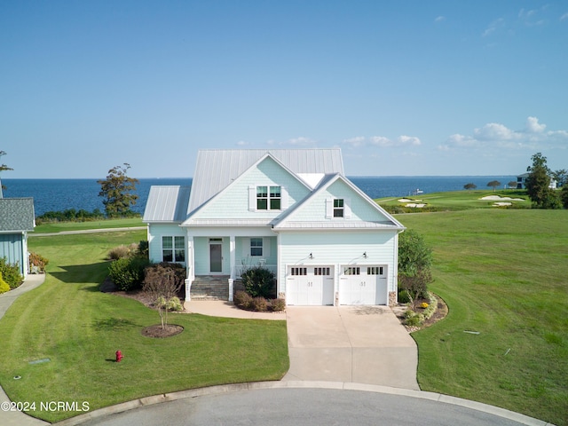 view of front of house with a front yard, a garage, covered porch, and a water view