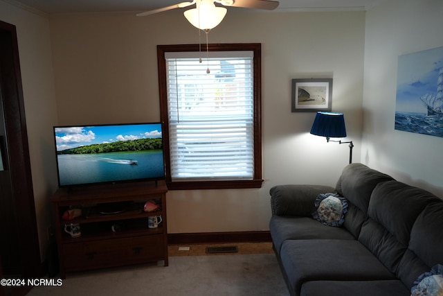 living area with baseboards, a ceiling fan, carpet floors, and ornamental molding