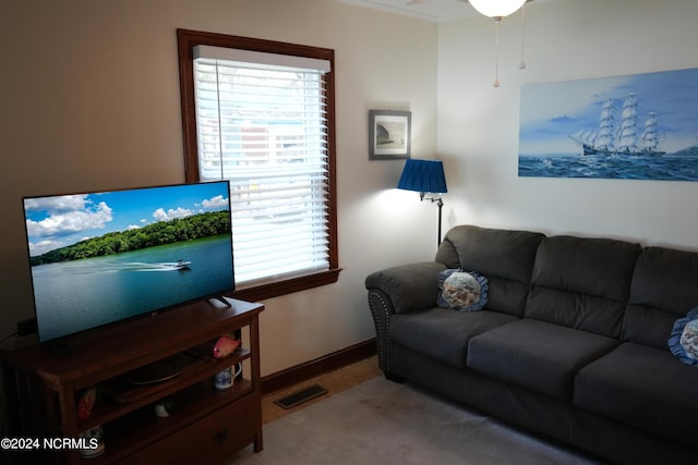 living area with crown molding, baseboards, visible vents, and carpet