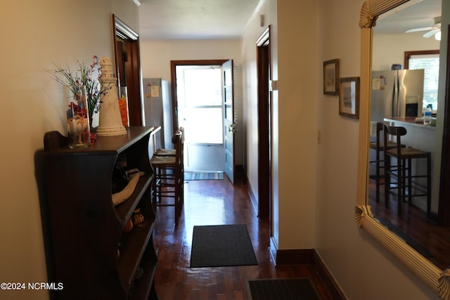 corridor featuring baseboards and dark wood-type flooring