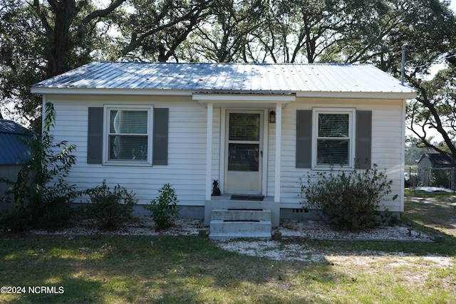 bungalow with metal roof, entry steps, and a front lawn