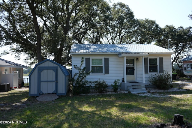 bungalow-style home with a storage unit, crawl space, a front yard, central air condition unit, and metal roof