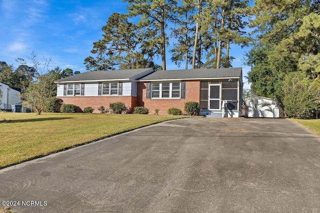 single story home with a front yard, a garage, an outbuilding, and a sunroom