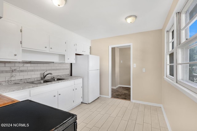 kitchen featuring electric range, backsplash, white cabinetry, sink, and white refrigerator