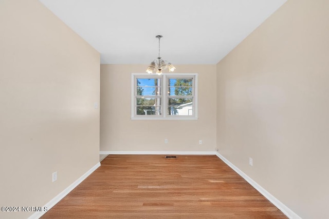 unfurnished dining area with light wood-type flooring and an inviting chandelier